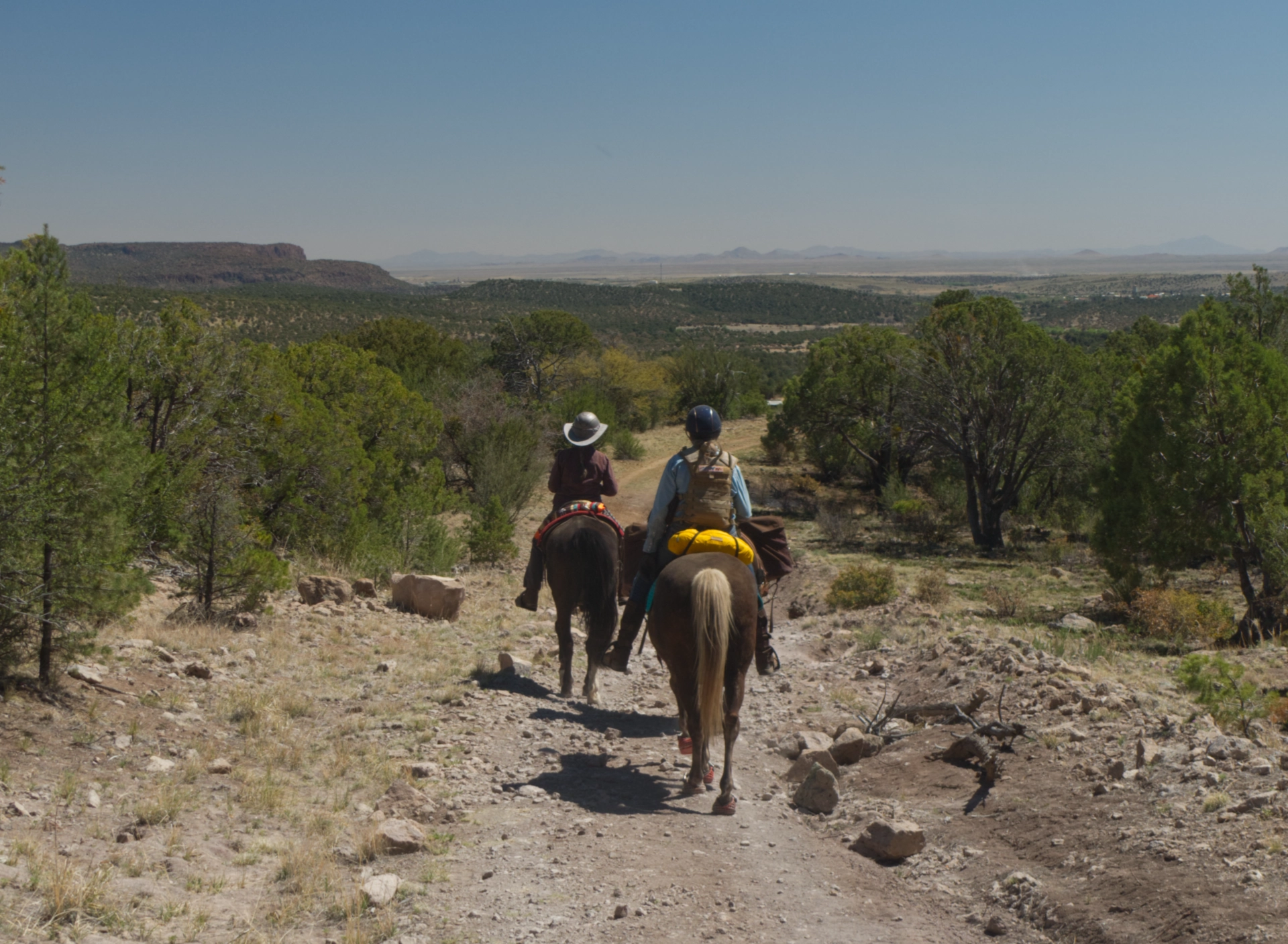 two women on horses riding toward the mountains