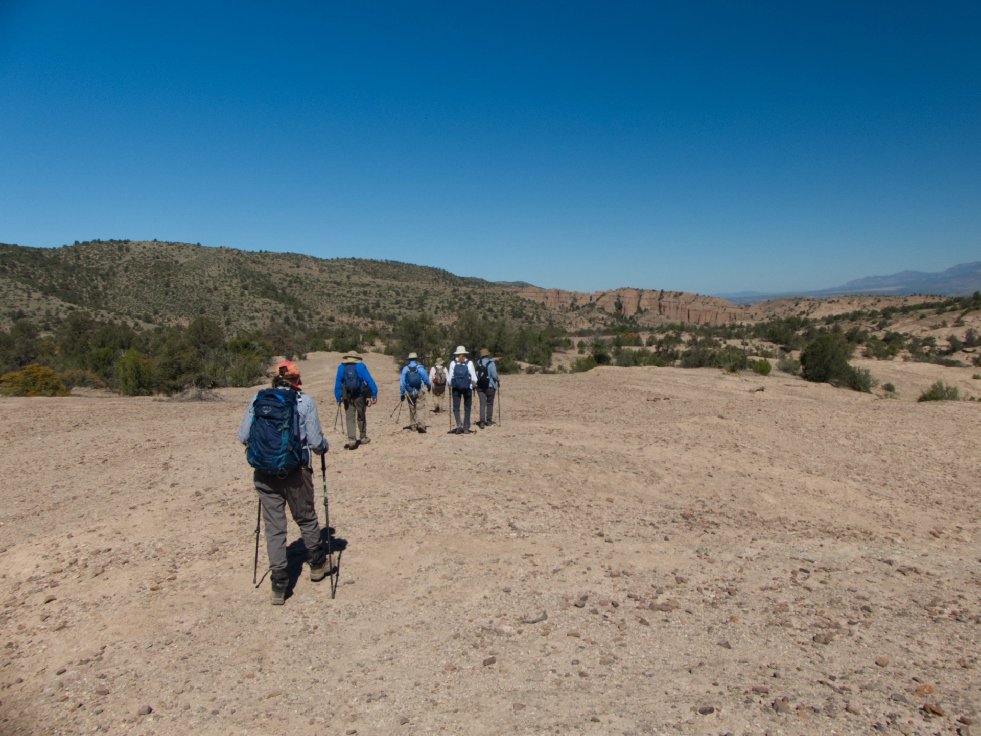 group of hikers crossing a stony plain with mountains in the distance