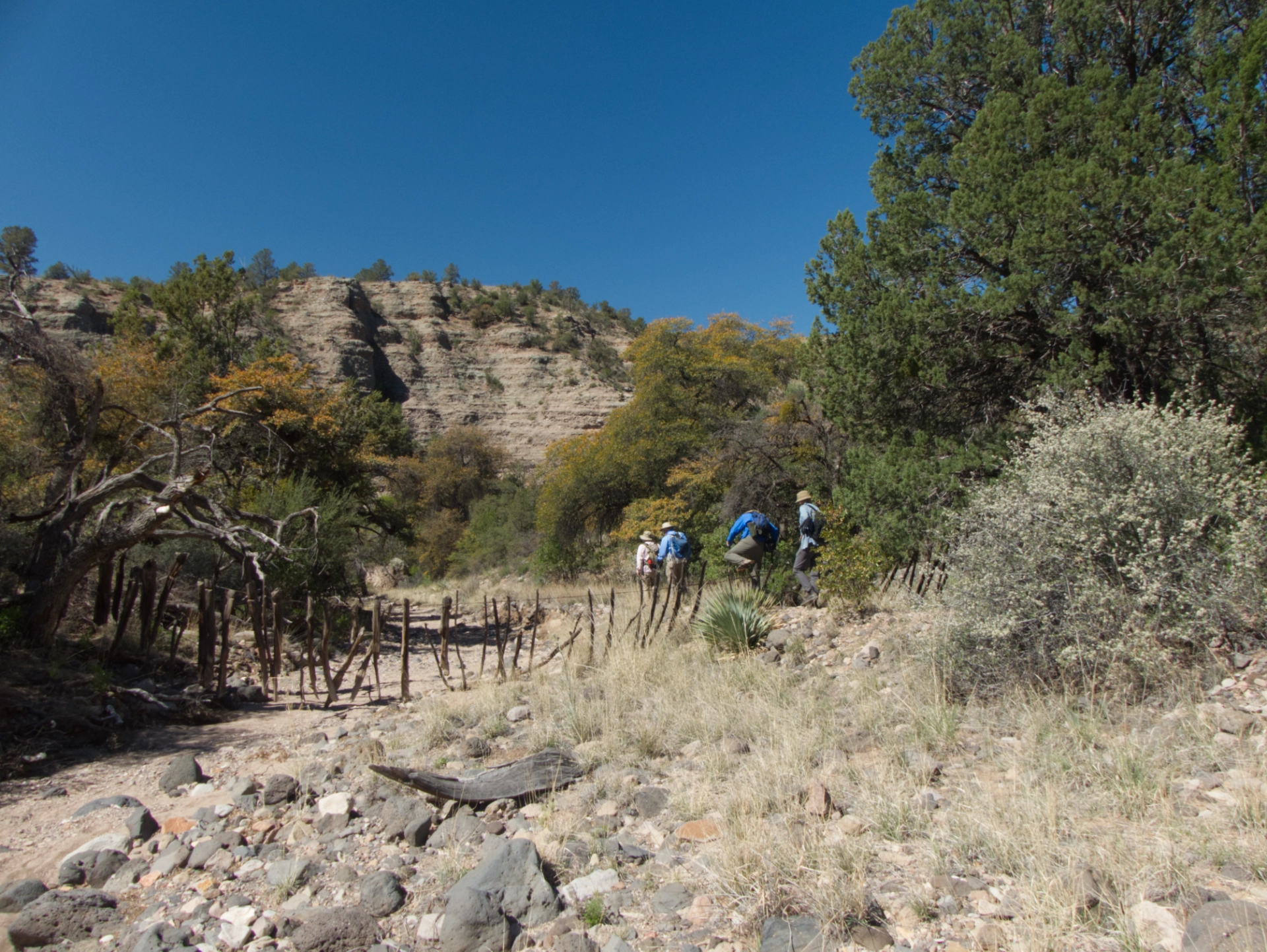 hikers going over an old fence across a dry stream