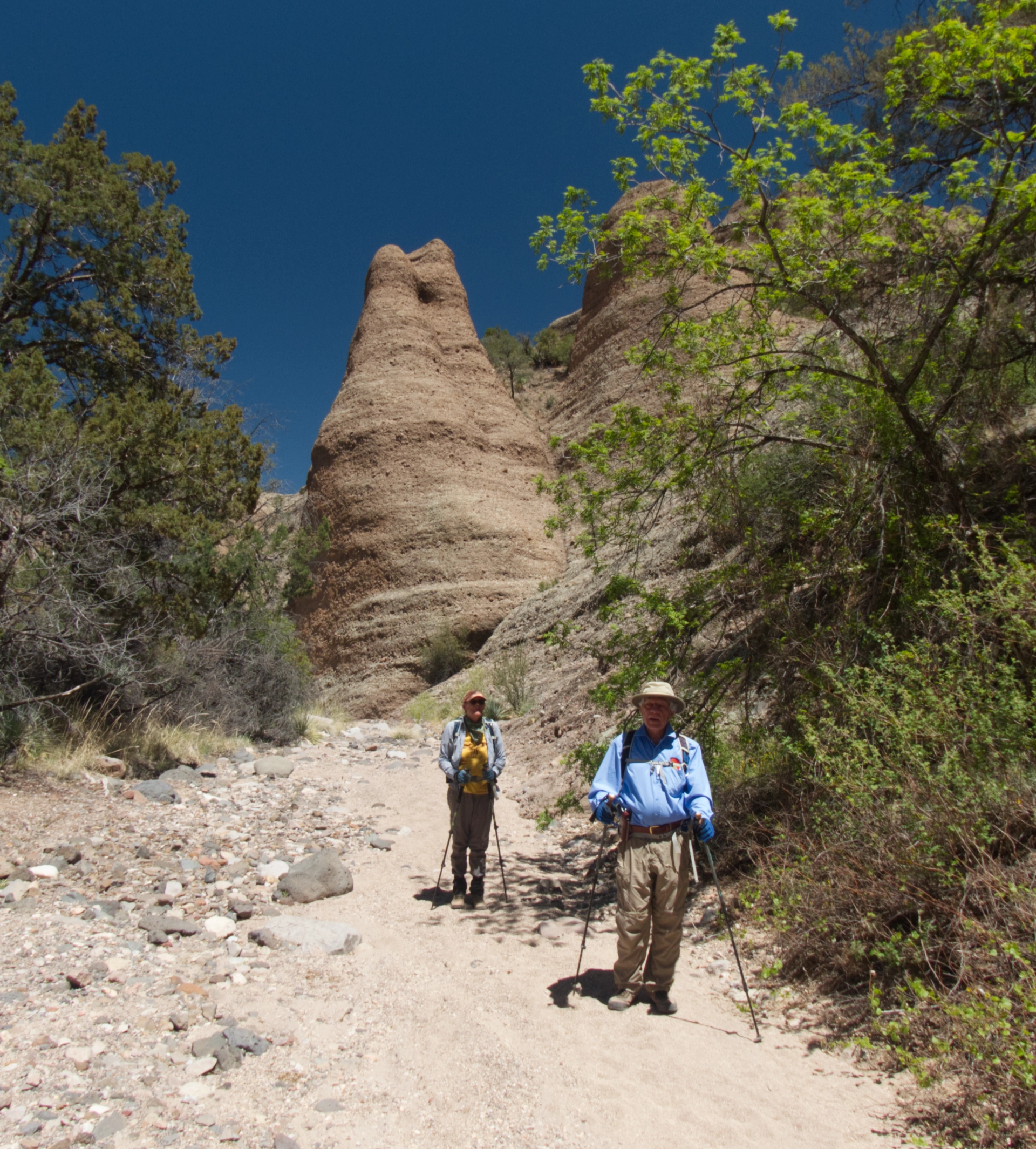 man and woman hiking out of the canyon with hoodoos behind them
