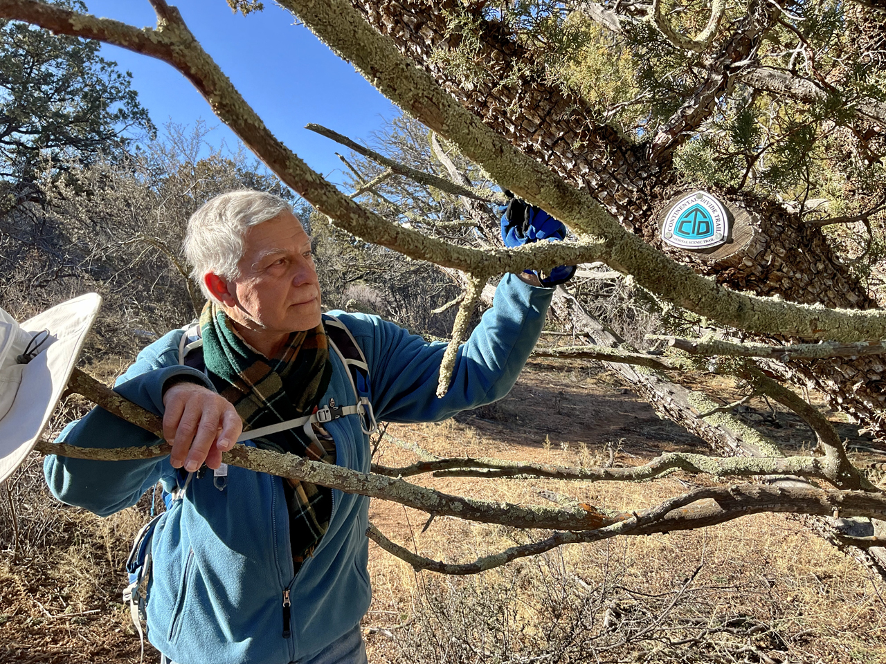 Dennis with CDT sign on an alligator juniper